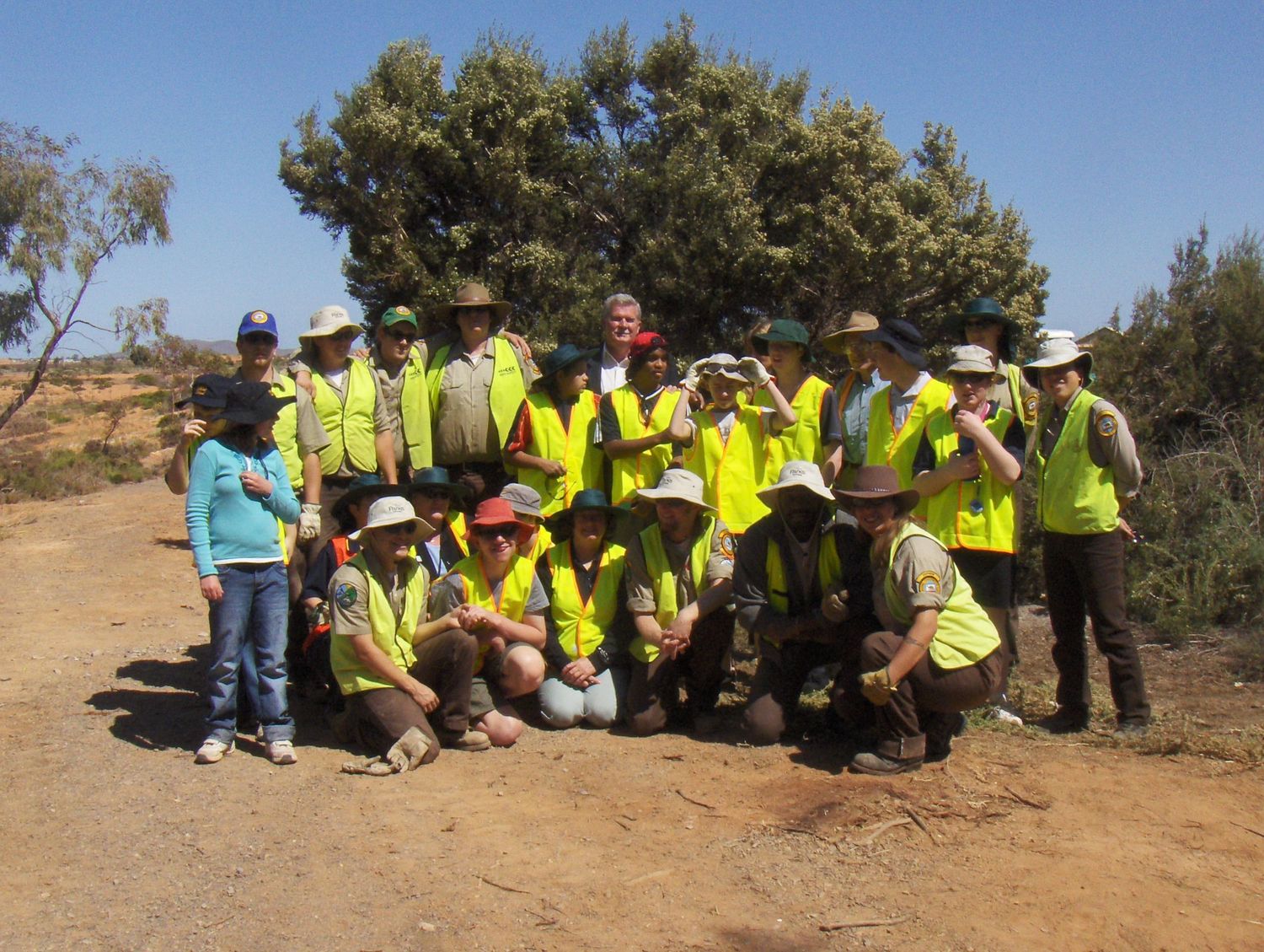 Group photo of research team members wearing high-visibility vests in an outdoor field setting.
