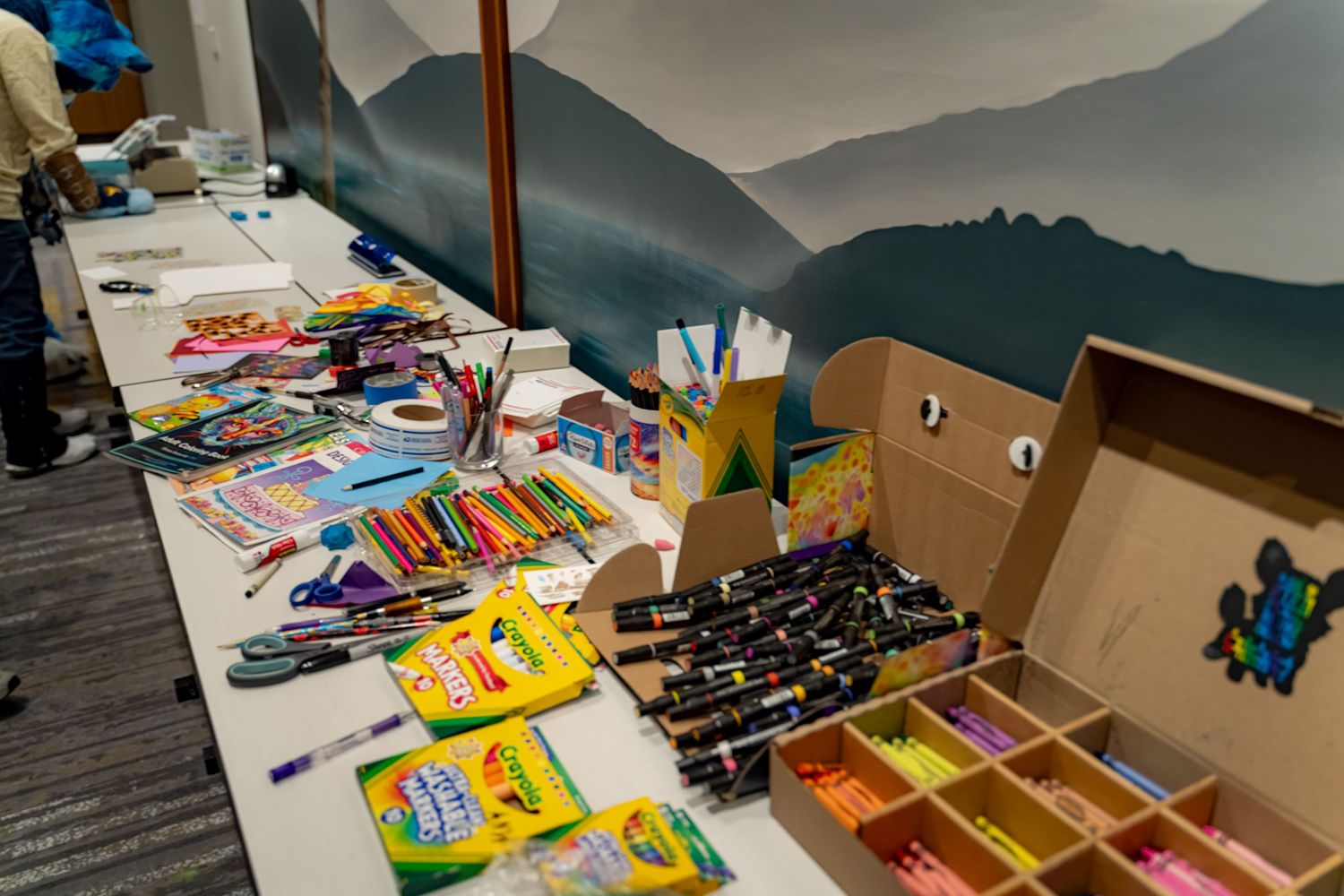 Colorful school supplies and snacks being organized and packed into cardboard boxes for donation or distribution.