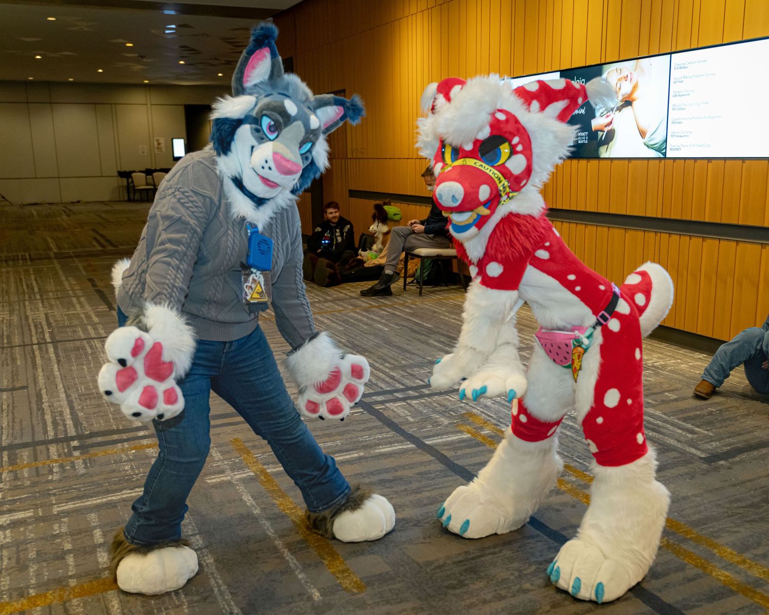 Several fursuit characters interacting and playing together on a carpeted convention floor.