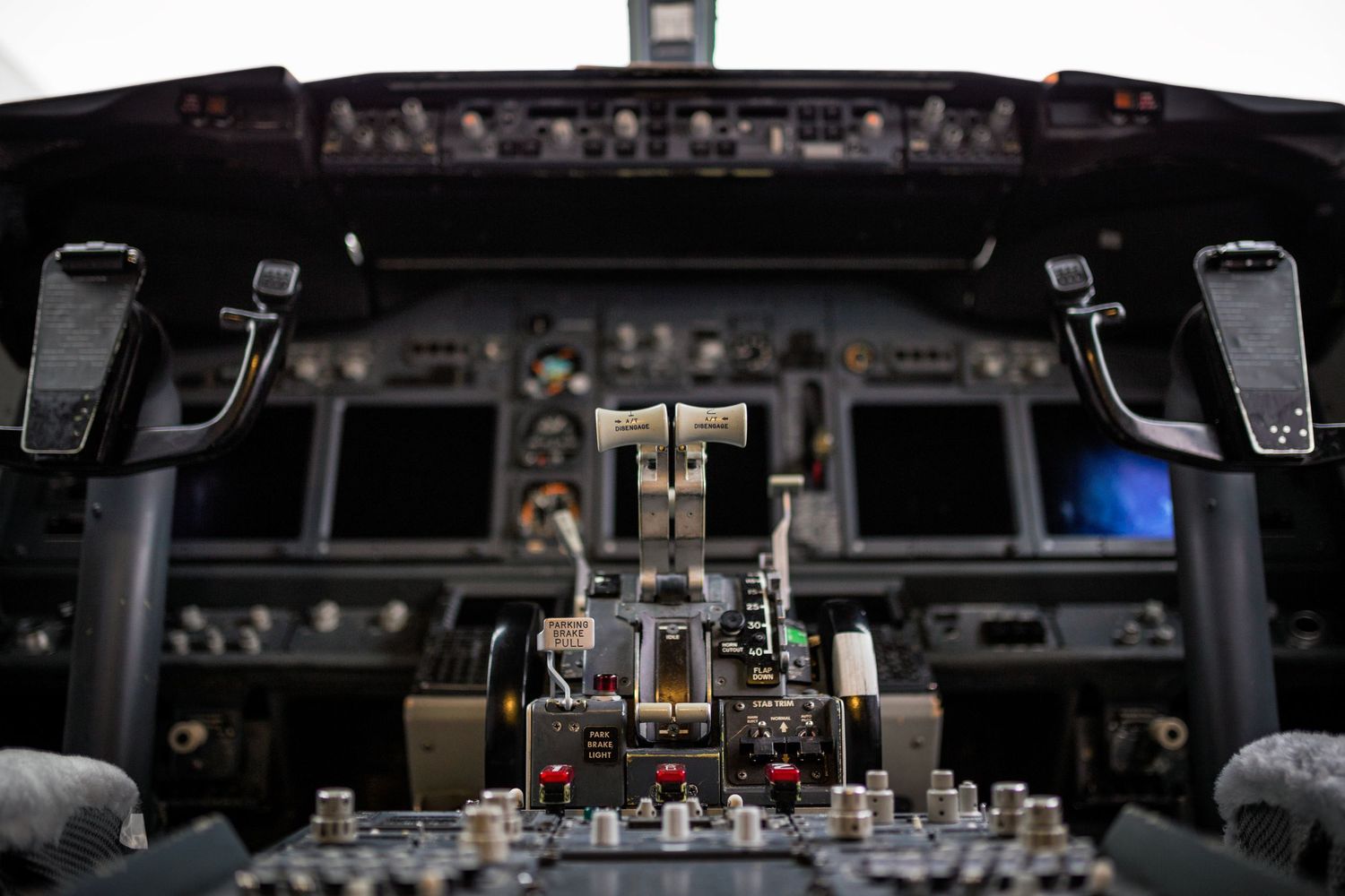 Dark interior view of modern aircraft cockpit dashboard with illuminated displays.