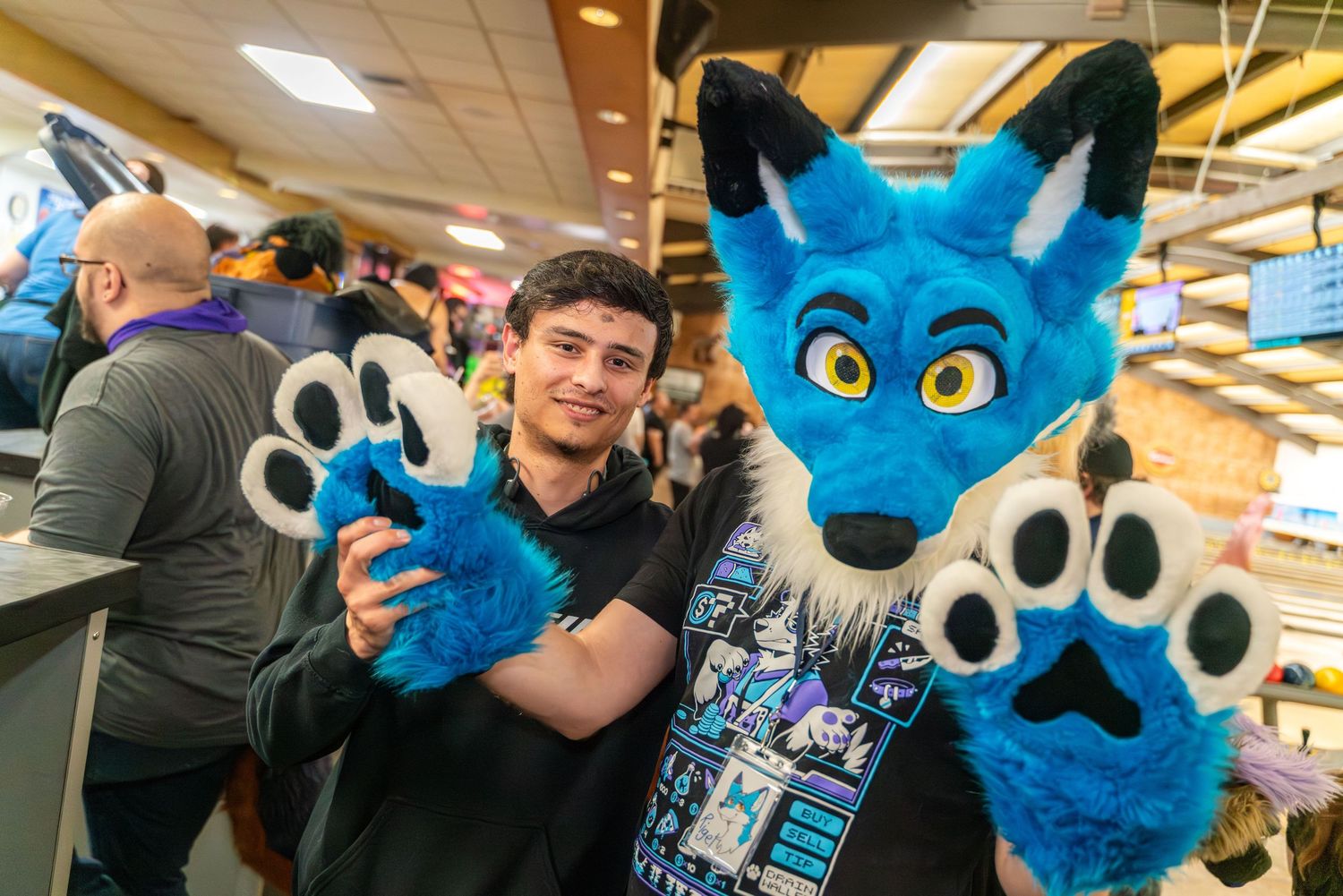Blue and white fursuit characters posing together at a bowling alley.