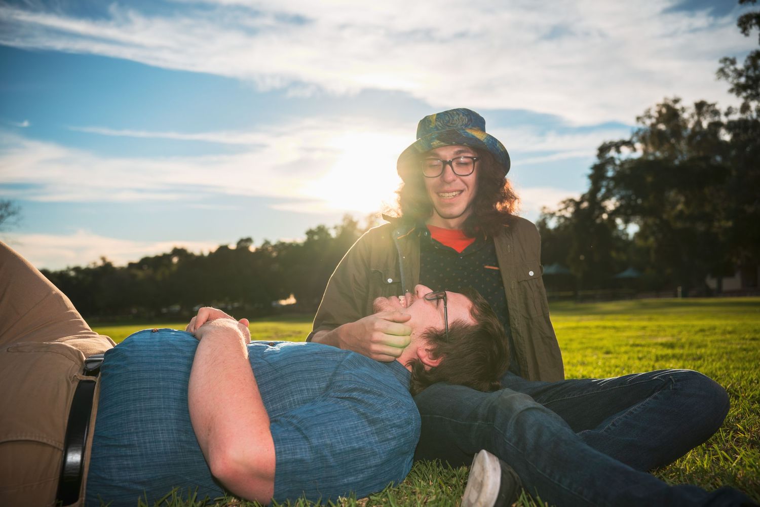 Golden sunset over grassy field with lens flare creating warm atmospheric lighting.