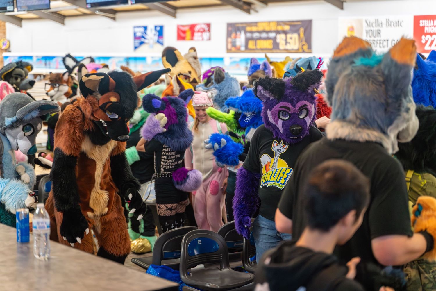 Wide shot of bowling alley showing crowd gathered for fursuit bowling event.