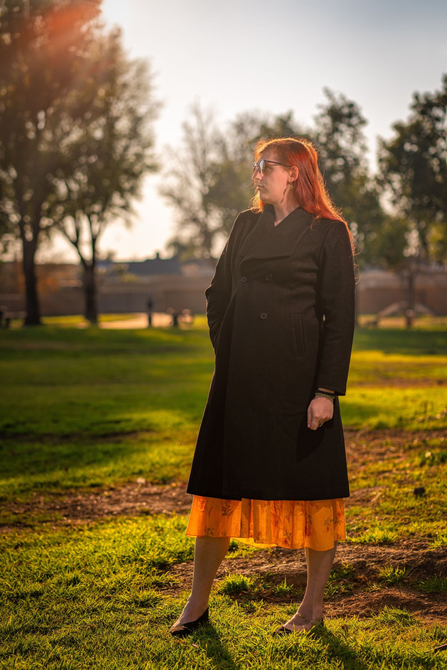 Artistic outdoor portrait in a grassy field during golden hour sunset.
