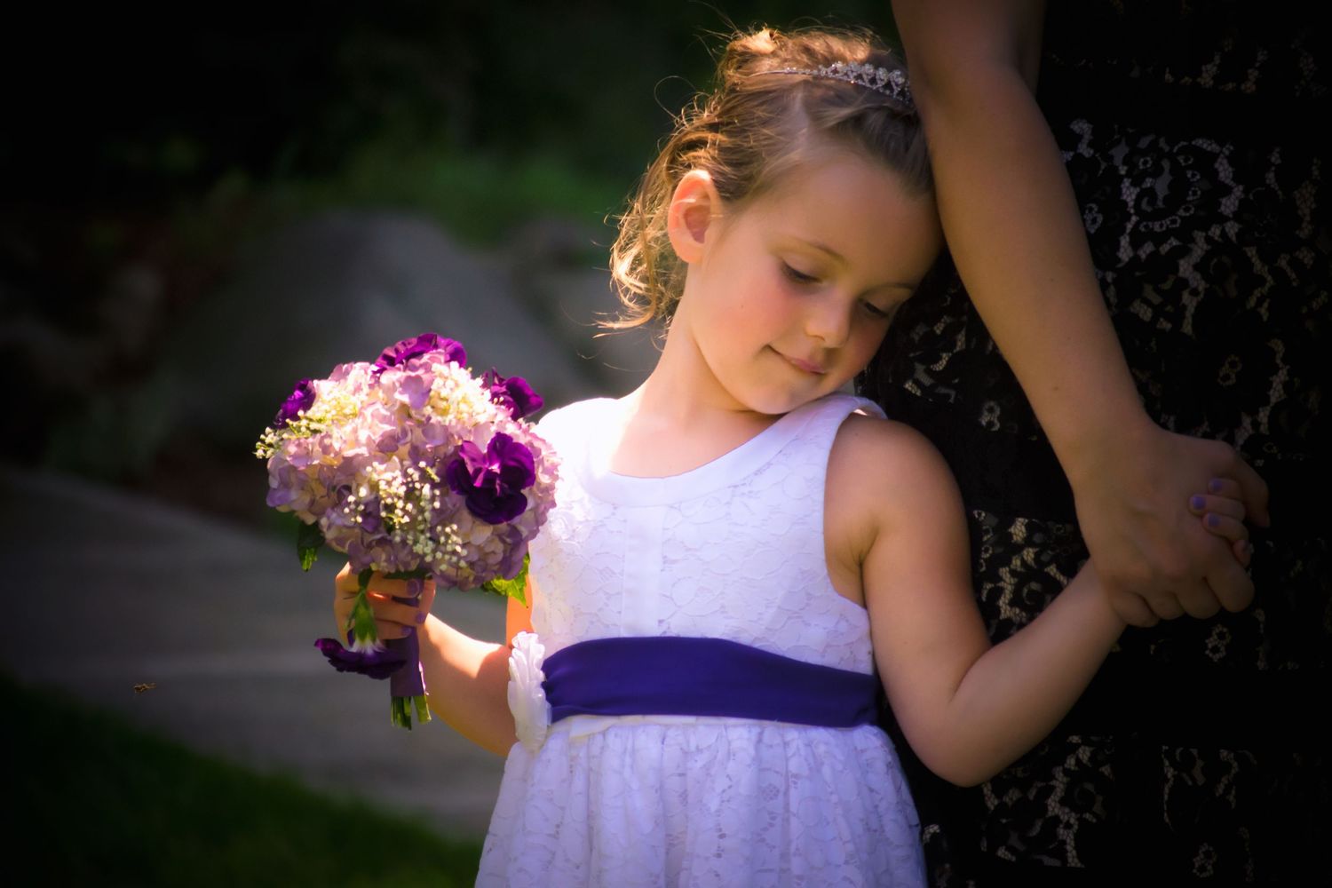 Young children in formal attire participate in an outdoor wedding ceremony.