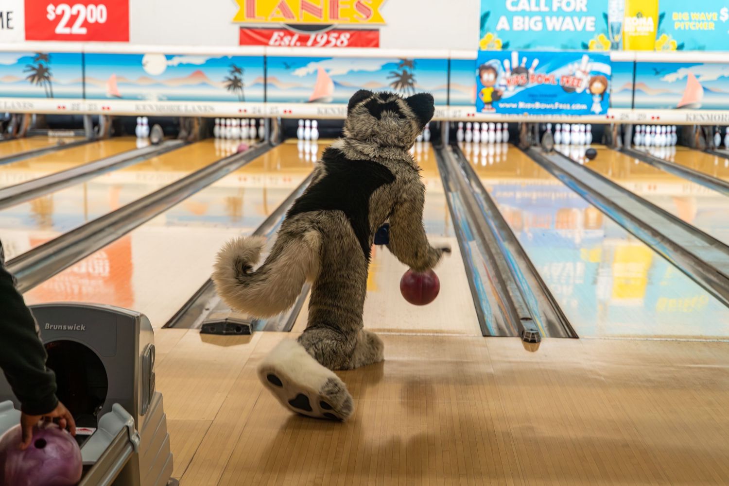 A fursuited bowler follows through on their bowling form after releasing the ball.
