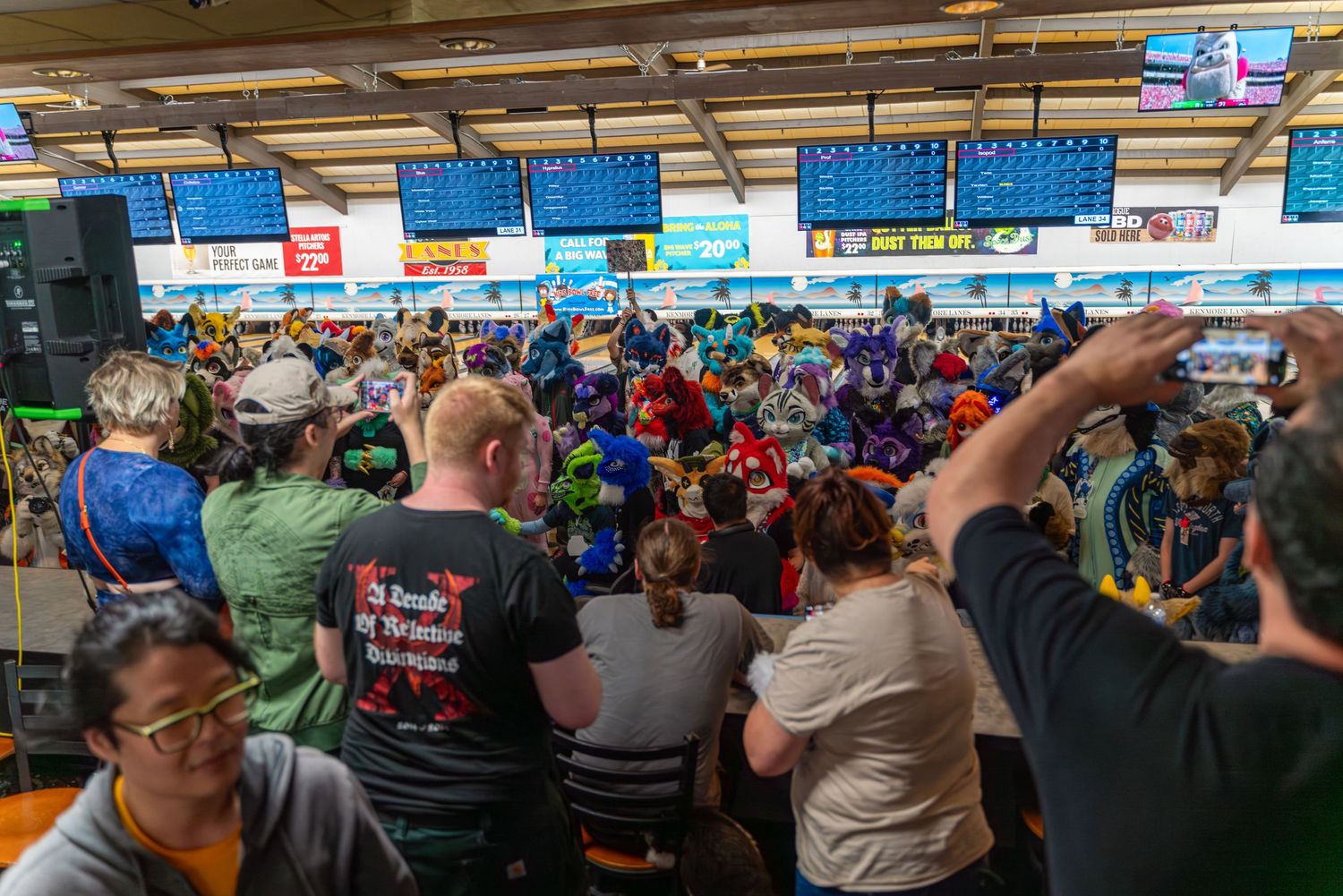 Crowded stadium seating area with blue overhead signage during a sporting event.
