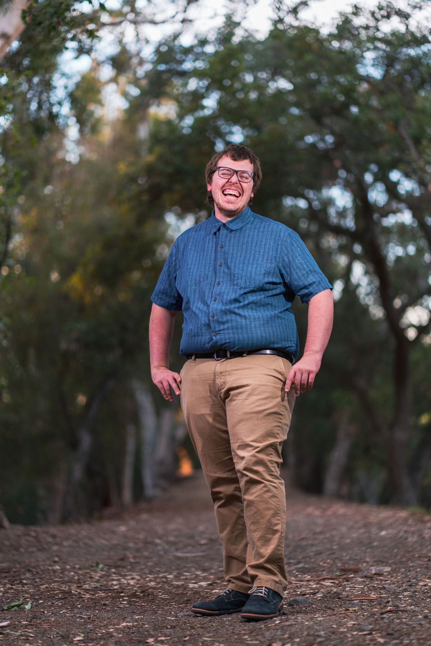 Person walking along a dirt path through wooded area wearing casual clothing.