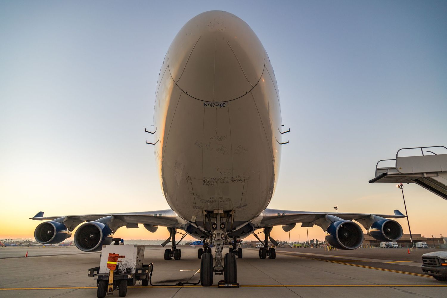 Panoramic view of large commercial aircraft fuselage and wings against sunset sky.