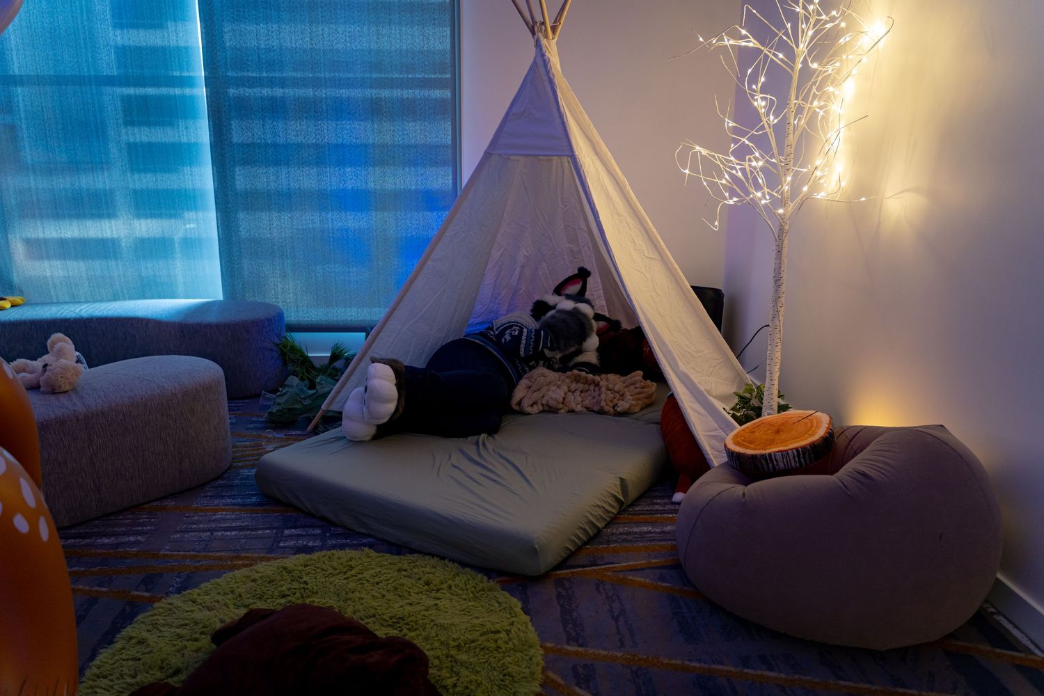 Cozy living room corner with glowing string lights creating a warm ambiance against blue-tinted walls.