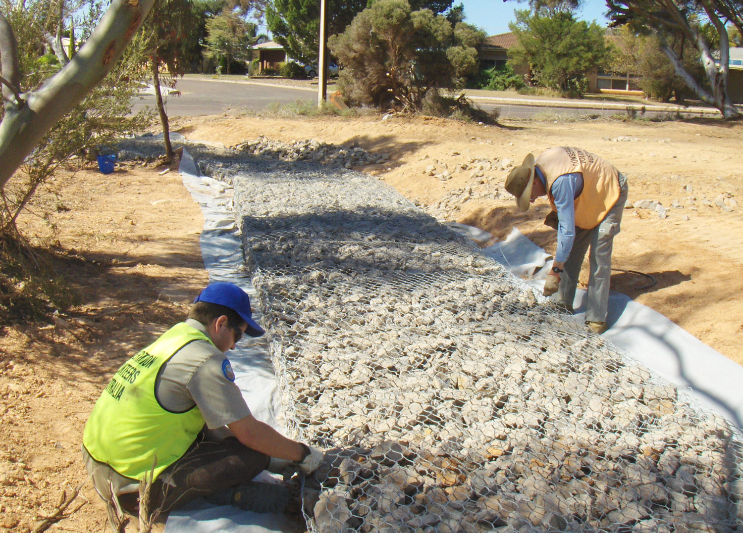 Scientists examining weathered rock formations and geological samples in an arid outdoor setting.