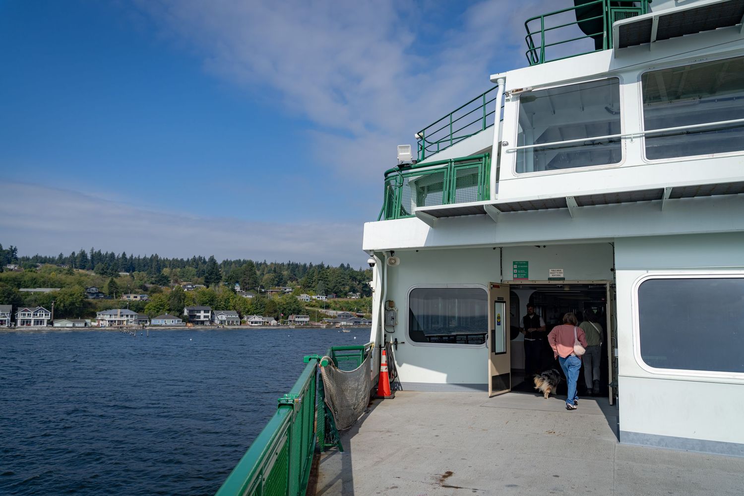 Wide view of a Washington State ferry deck with green railings and coastline in the background.