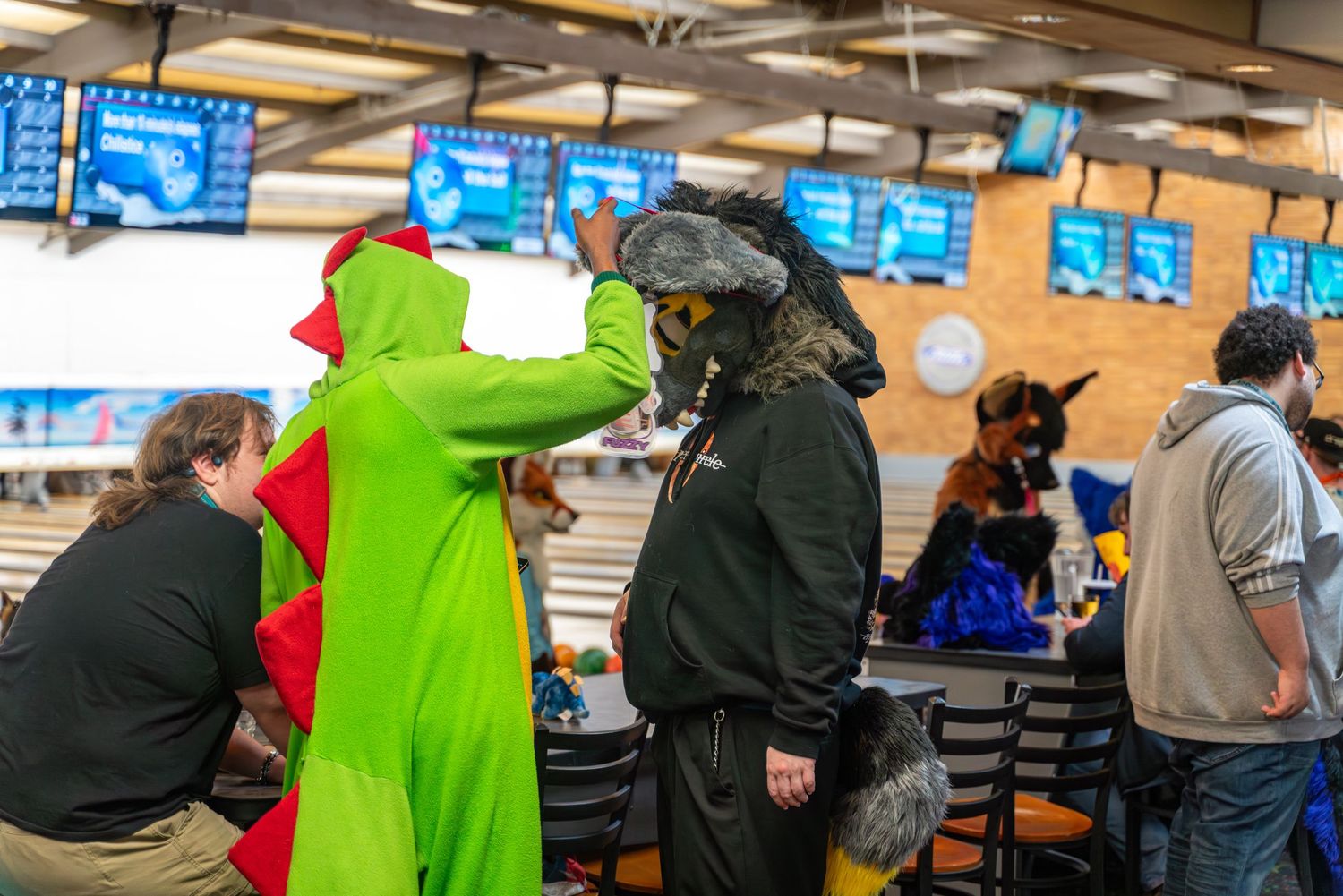 Crowded bowling alley with spectators watching fursuit bowling event.