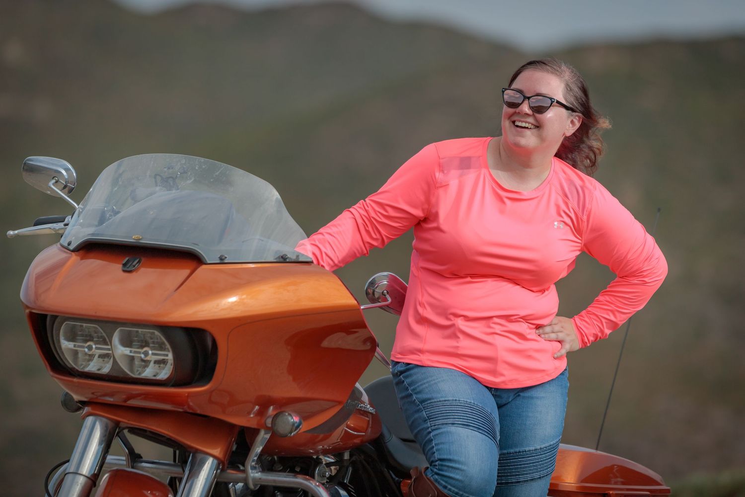 Orange Harley Davidson motorcycle on display with scenic background.