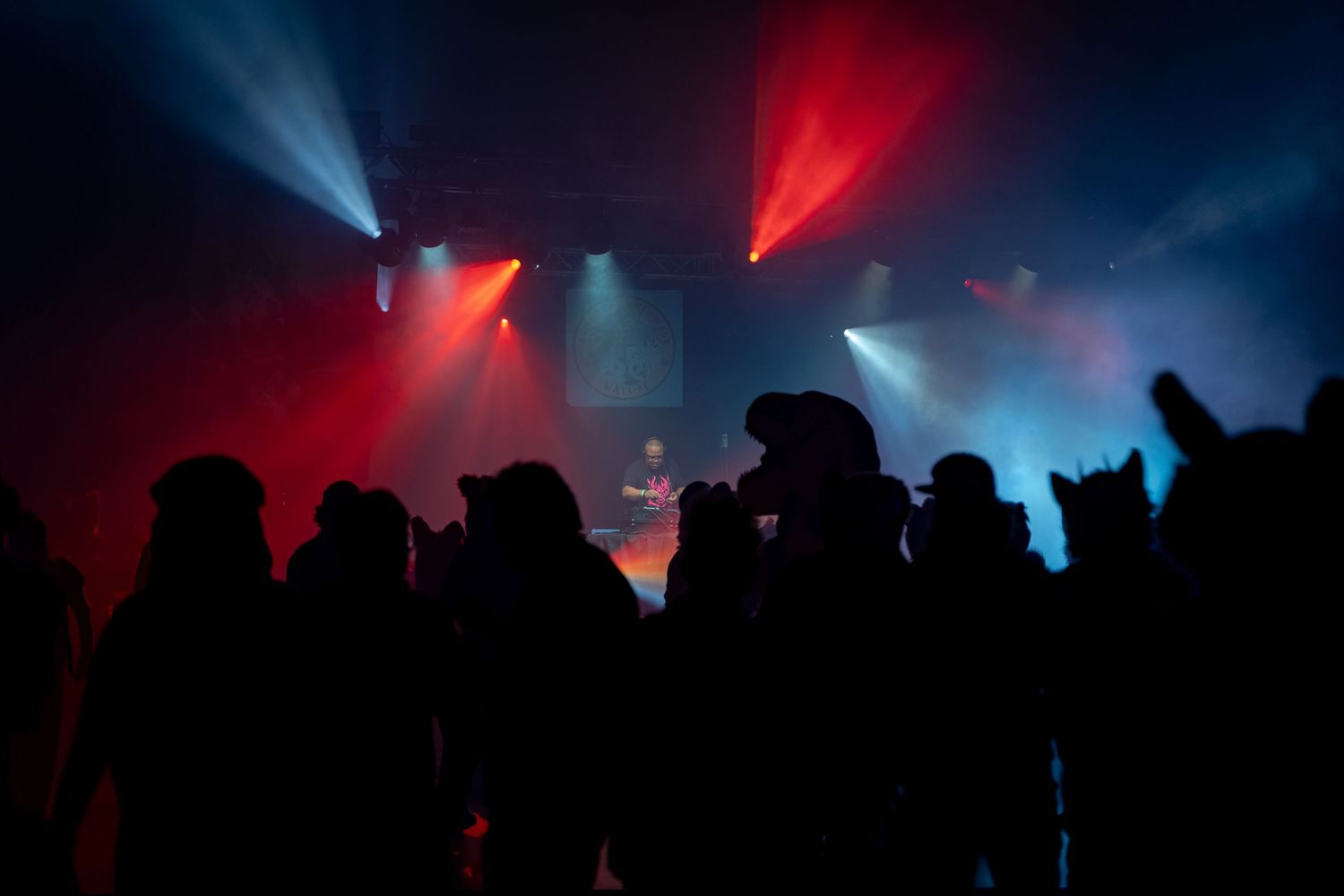 Concert crowd silhouettes against dramatic red and blue stage lighting at a live performance.