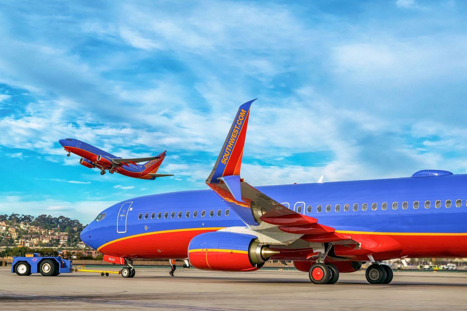 Row of Southwest Airlines aircraft lined up on tarmac under bright blue sky.