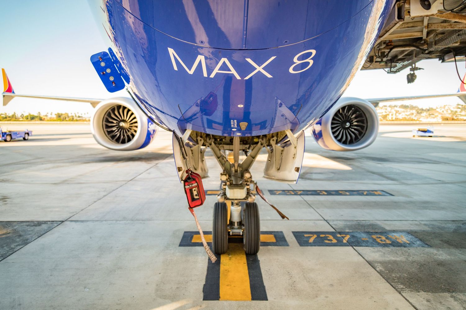 Boeing 737 MAX 8 aircraft nose and engines on tarmac during sunset.