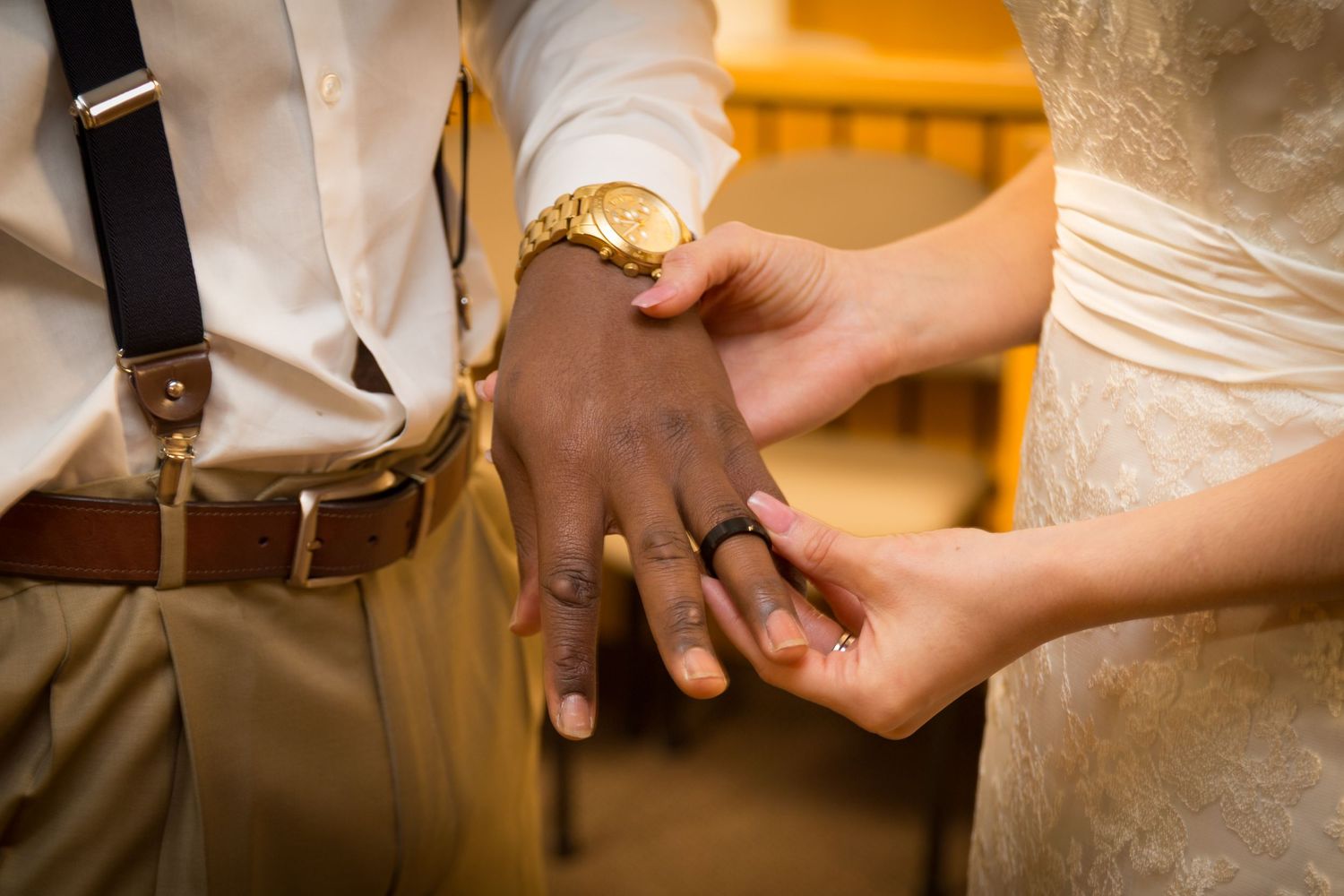 Close-up details of hands exchanging rings during a wedding ceremony.