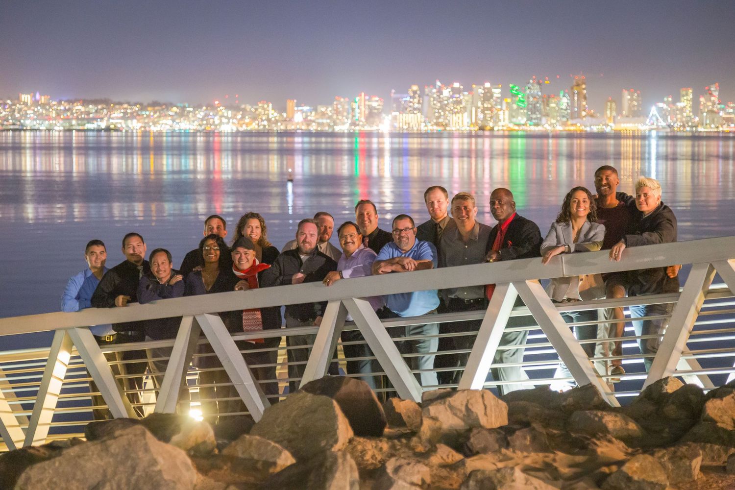 Group of people silhouetted against illuminated city skyline at night.