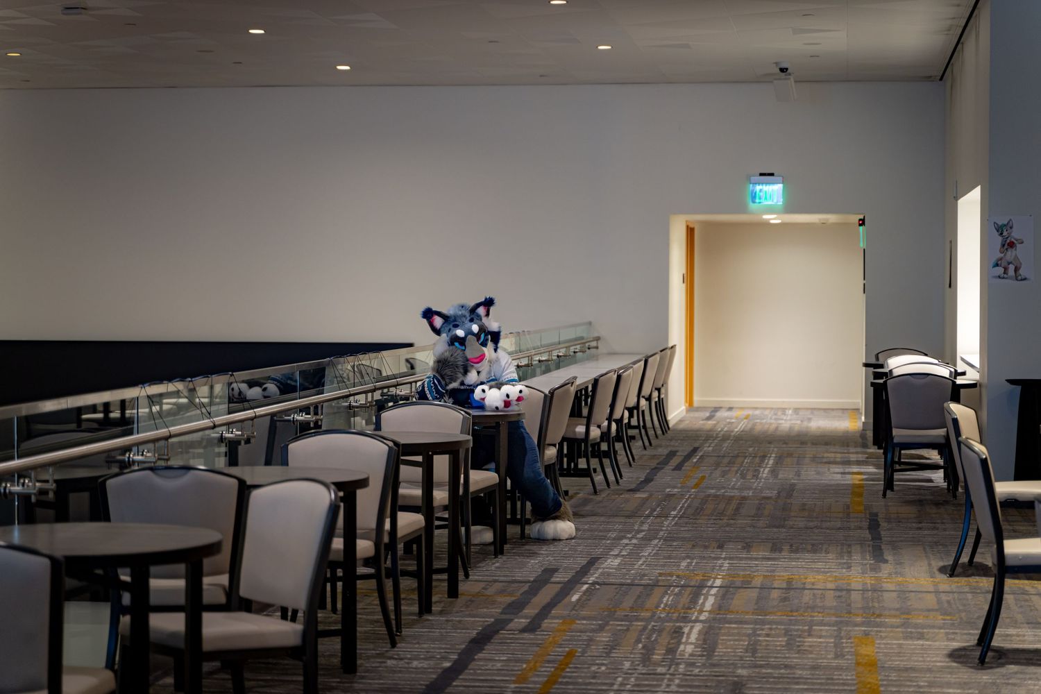 Empty cafeteria interior with dark tables and chairs arranged in rows under recessed lighting.
