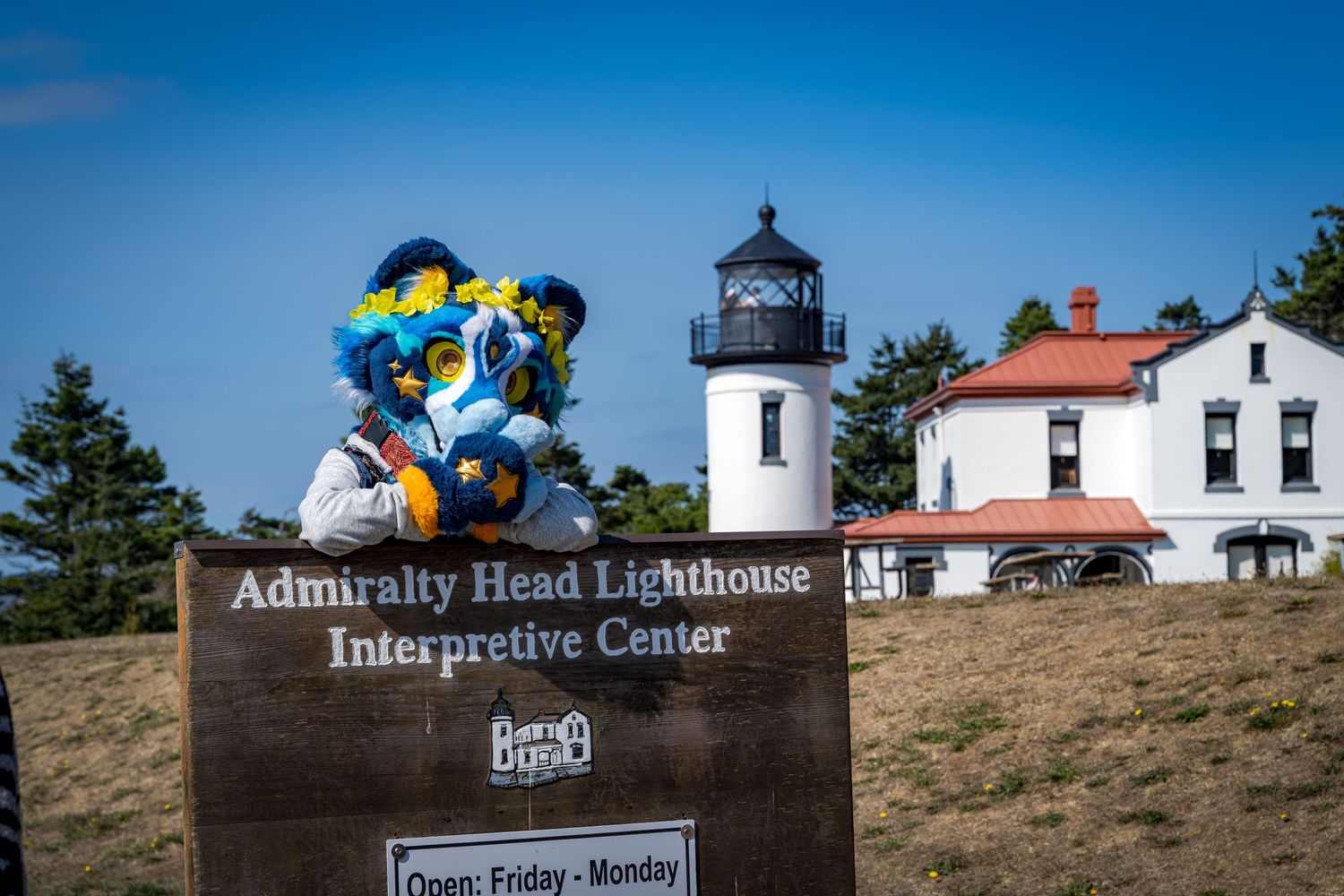 Admiralty Head Lighthouse Interpretive Center sign with lighthouse building in background.
