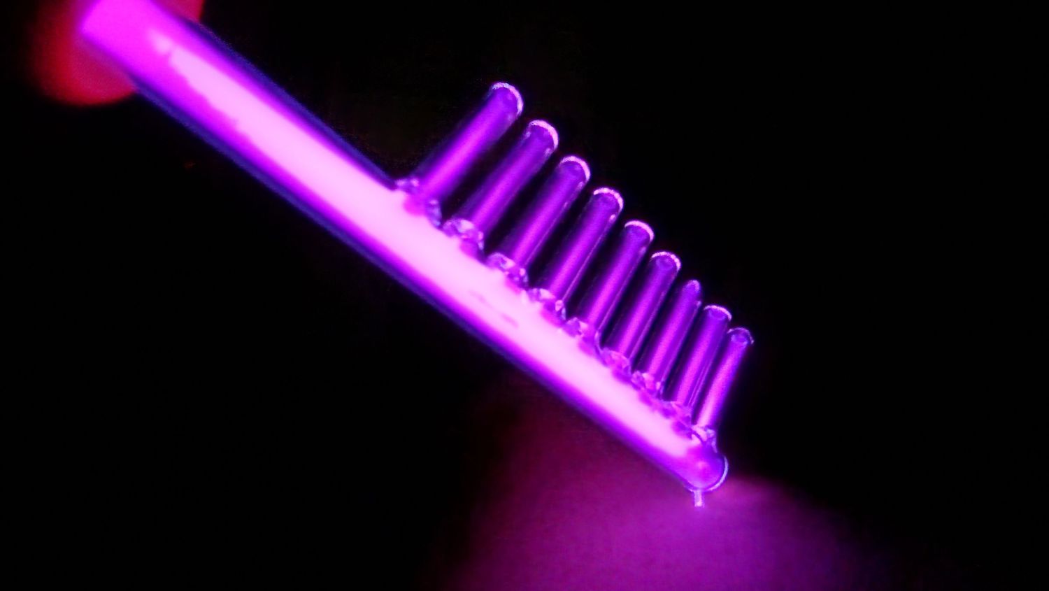 Purple neon light glowing in darkness with geometric pattern.