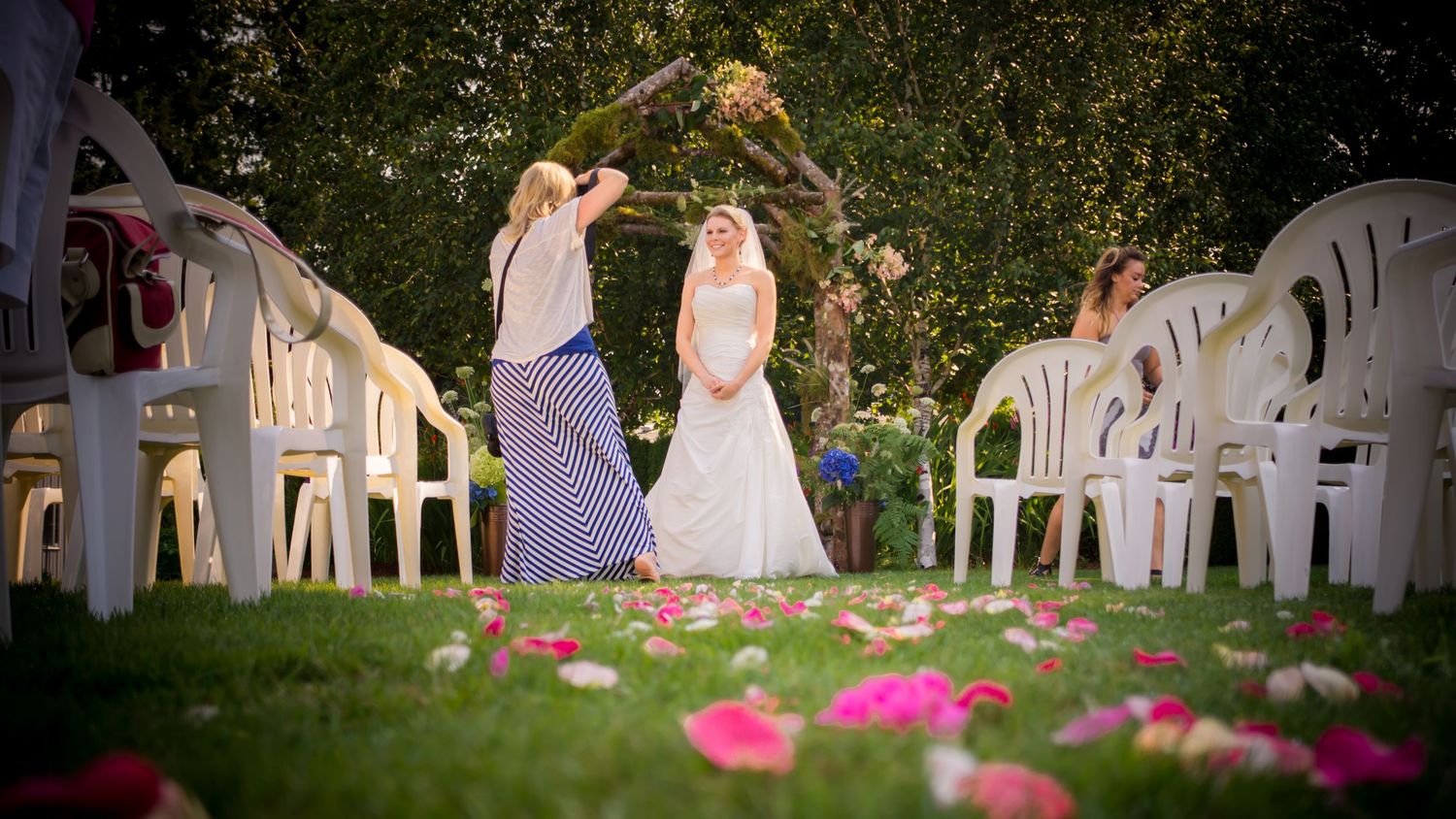 Wedding ceremony chairs arranged in rows on a manicured lawn with floral decorations.