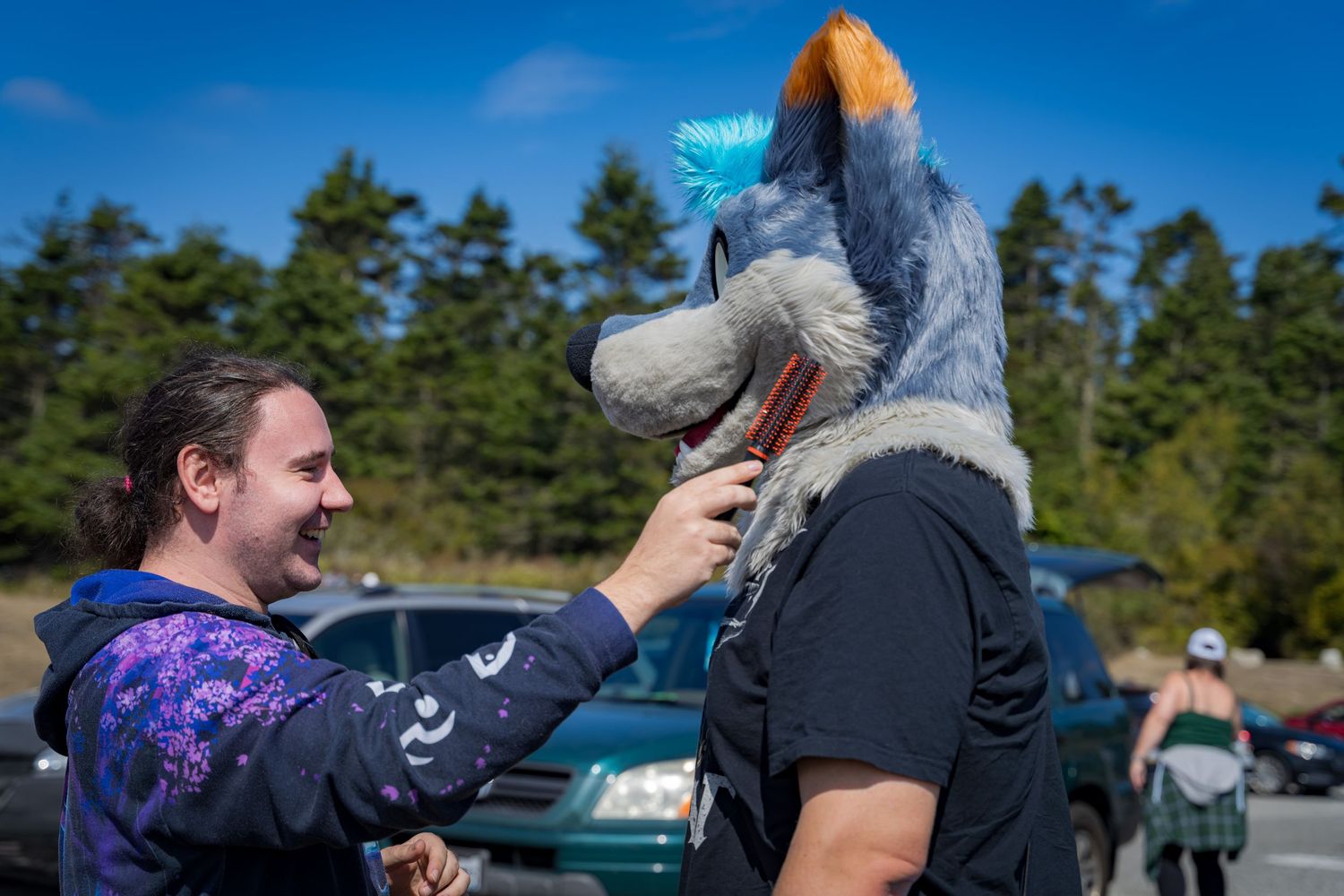 Fursuit interaction outdoors with lighthouse and trees in background.