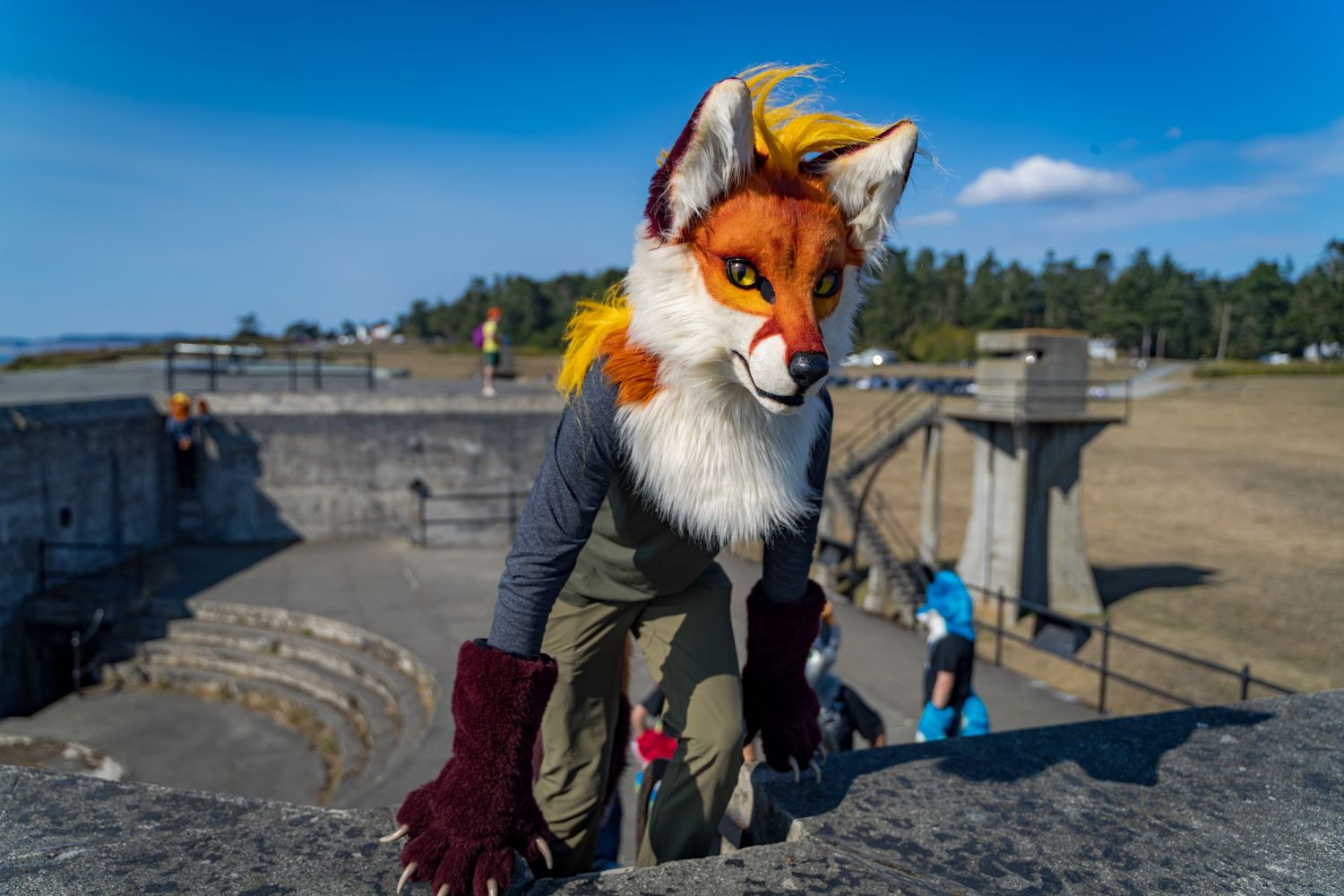 Fursuiters in colorful costumes explore the exterior of a historic military bunker.