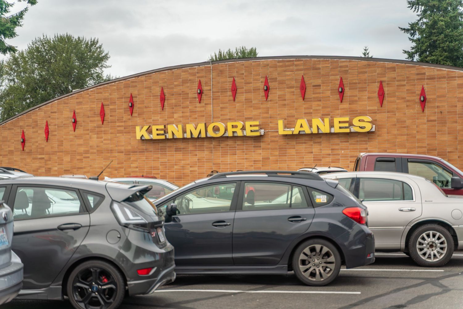 Exterior view of a bowling alley building with parked cars in front.