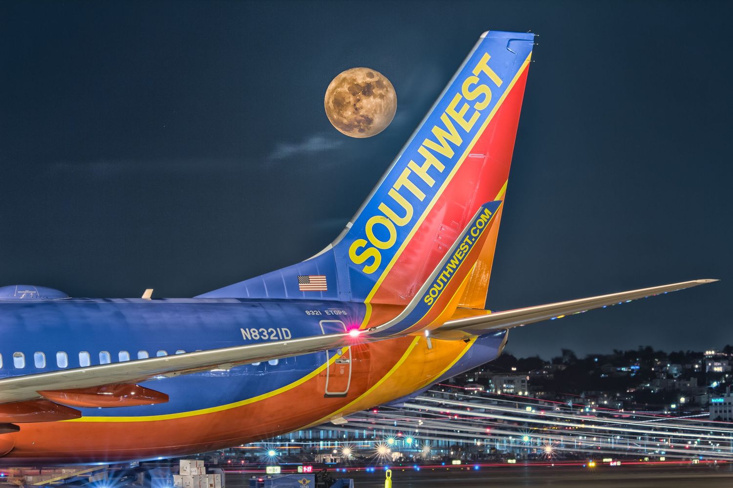 Southwest Airlines aircraft tail fin photographed against night sky with full moon.