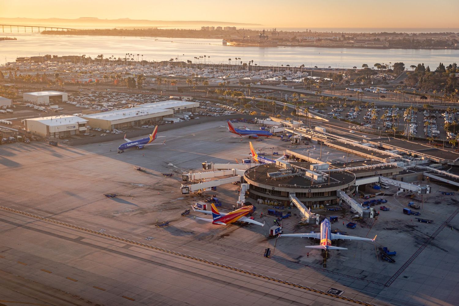 Sunset aerial view of commercial airport terminal with multiple planes parked at gates.