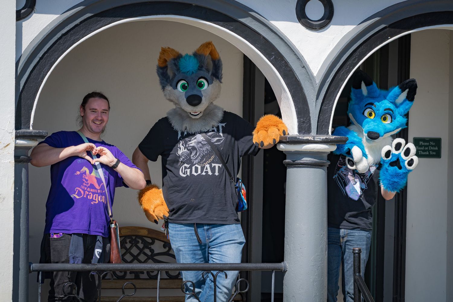 Costumed characters gather under arched colonnade of historic building.
