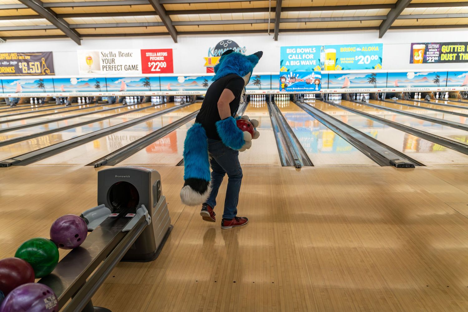 Wide angle view of bowling lanes with bowlers in colorful costumes.