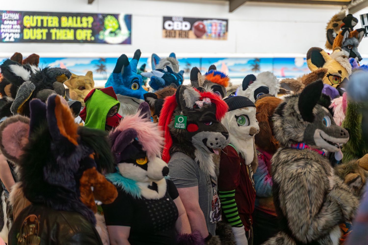 Fursuit bowling event with participants in colorful animal costumes gathered at a bowling alley.