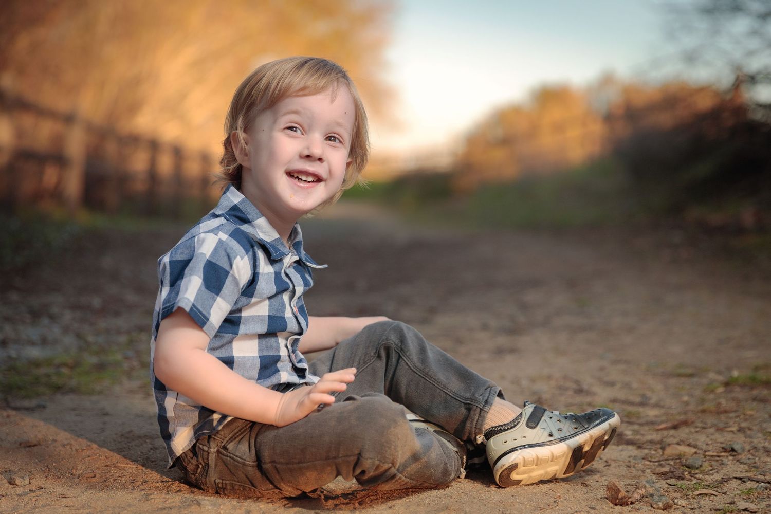 Child lying on ground outdoors during golden hour photography session.