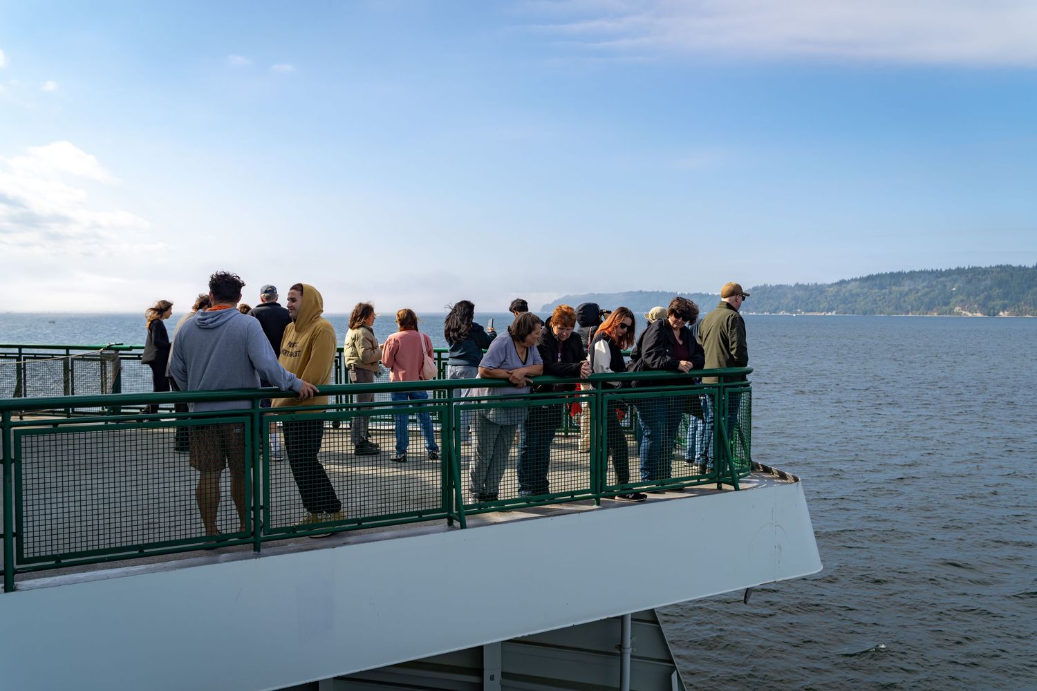 Ferry deck observation area with passengers looking out over the water on a sunny day.
