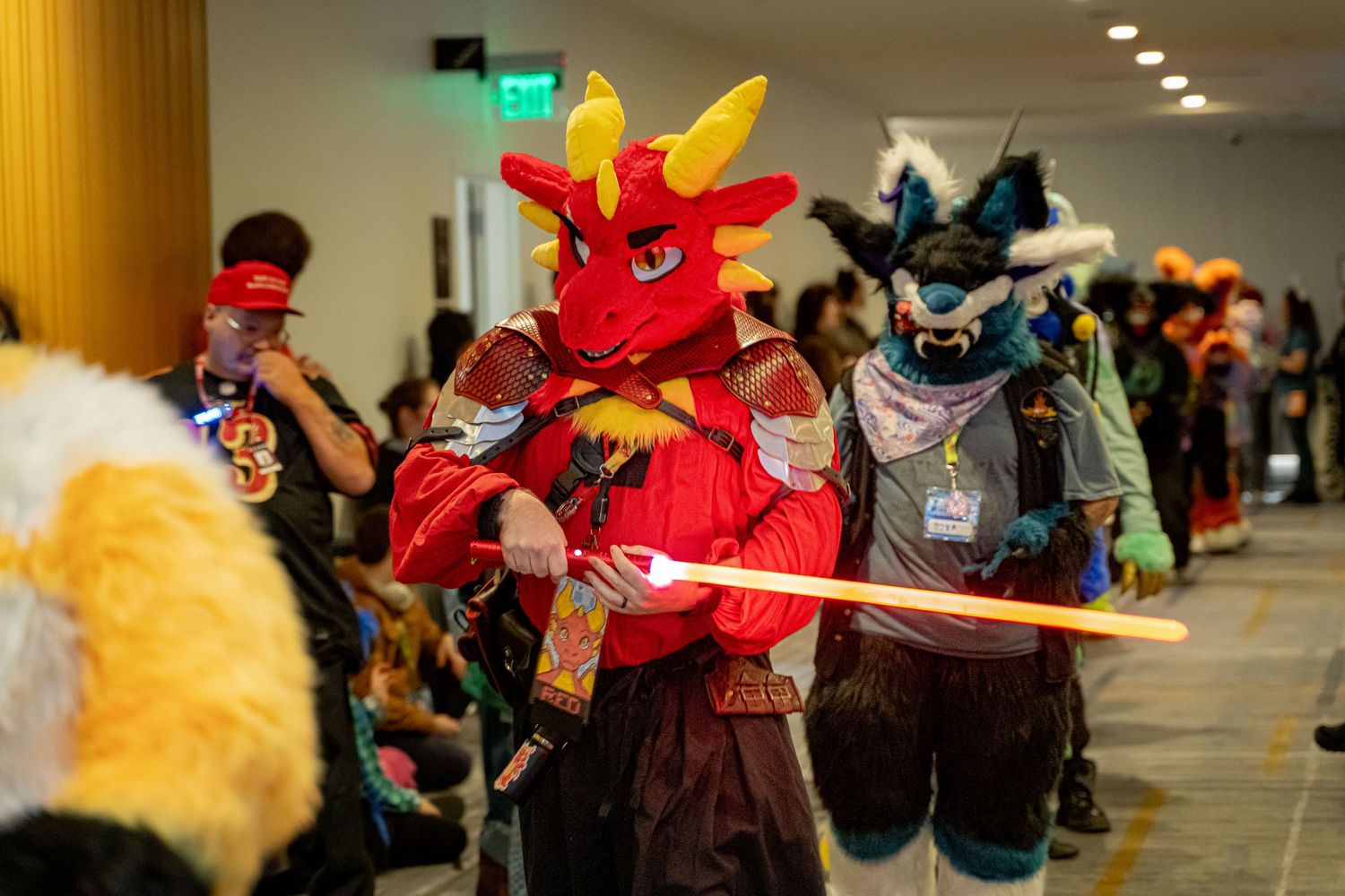 Cosplayers dressed as fantasy characters pose with prop weapons at an indoor convention event.