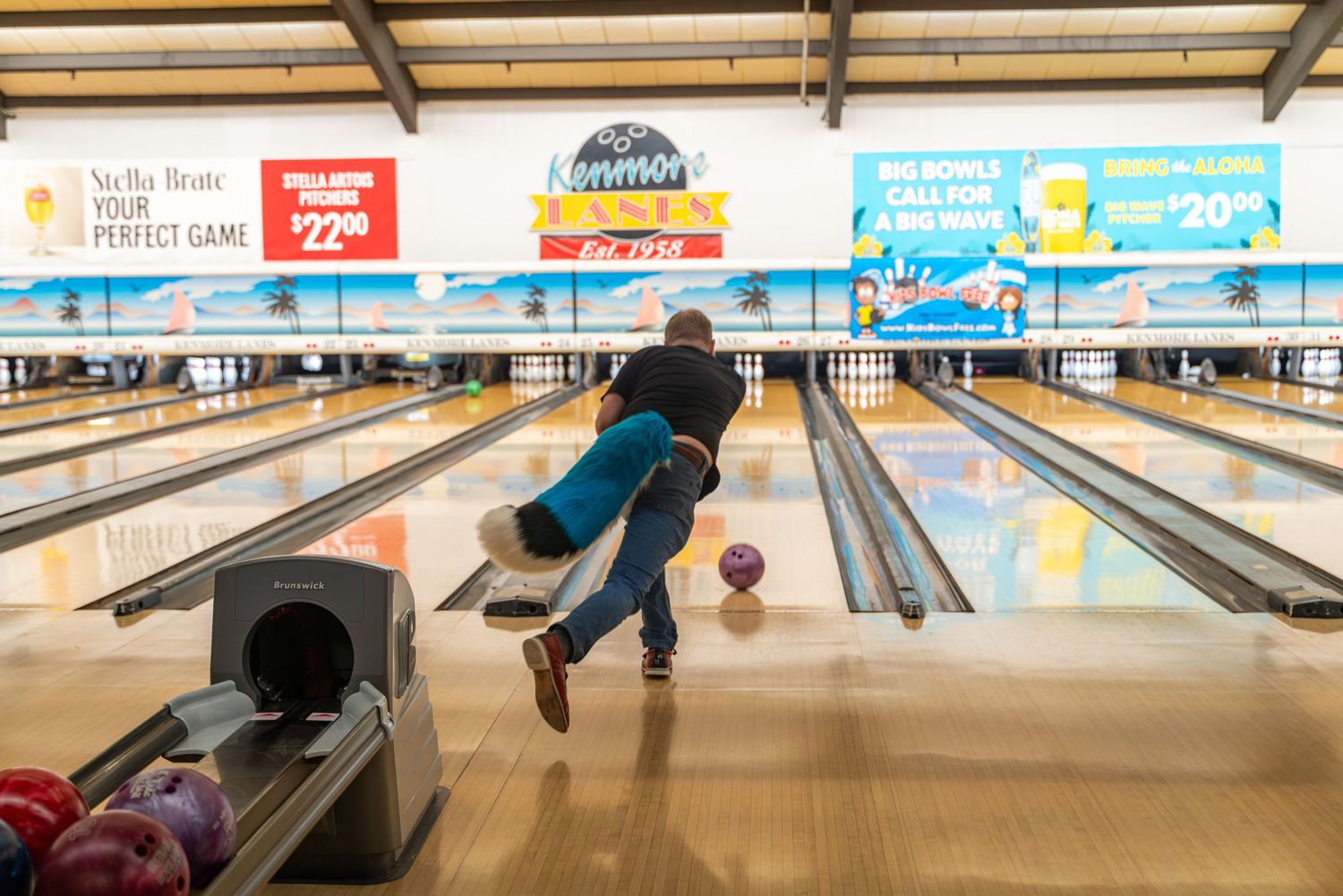 Bowling alley lanes visible with blue costumed characters posing in formation.