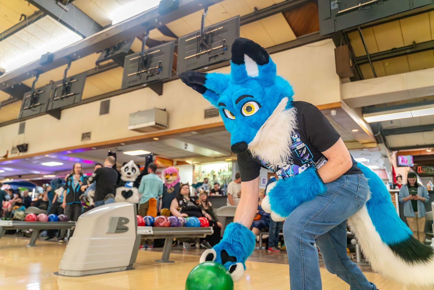Blue costumed characters crouching in formation at a bowling alley venue.