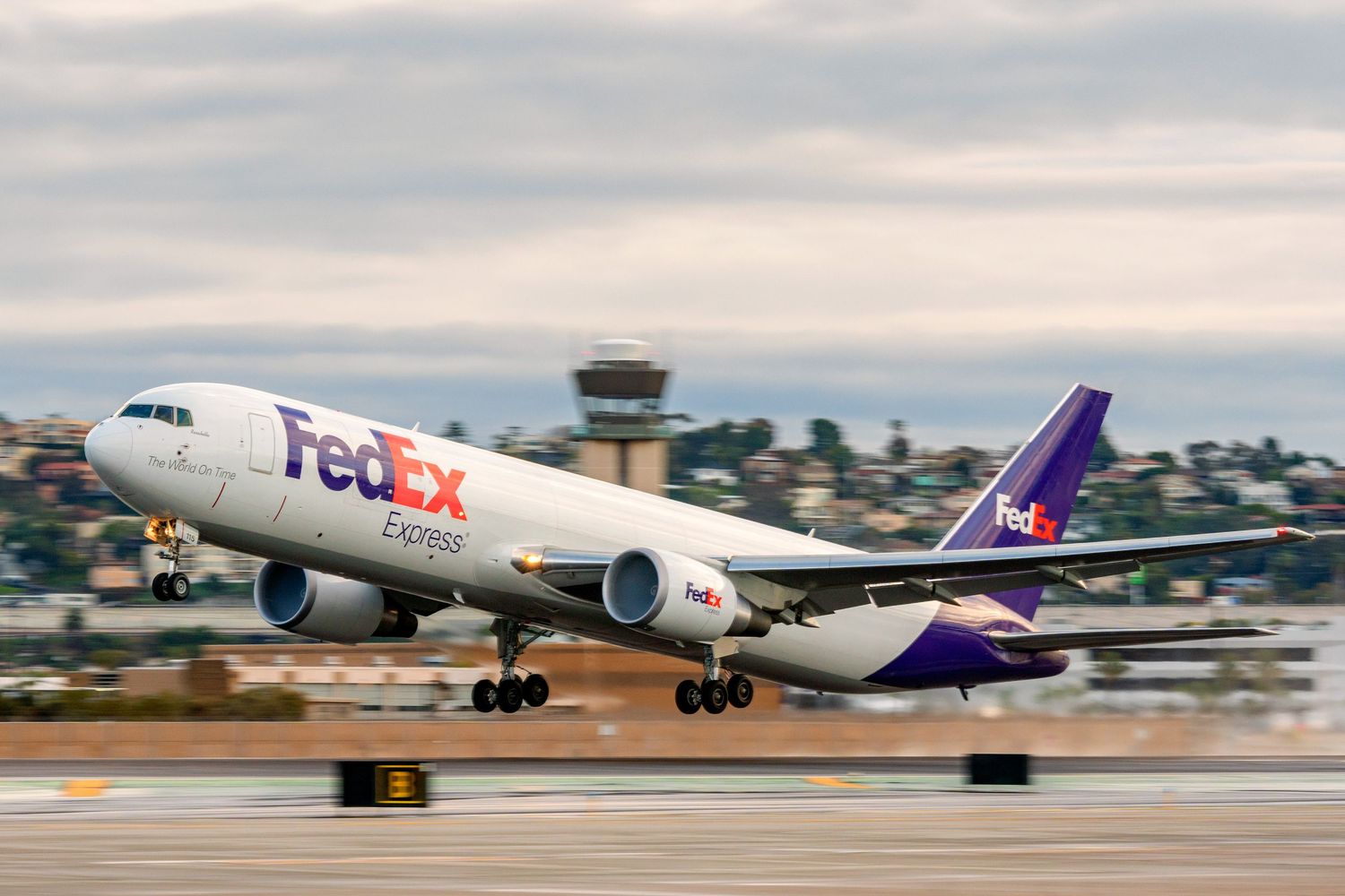 FedEx cargo planes taking off and landing on airport runway in sequence.