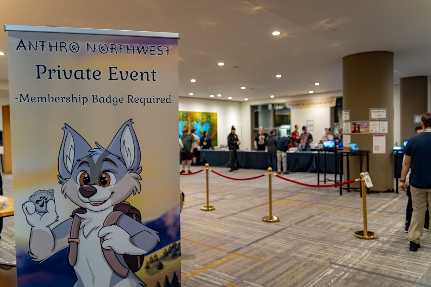 People wait in line at a convention center with stanchions and signage for a private event.