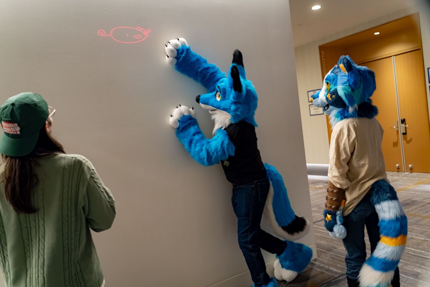A fursuit character with blue and white fur poses in various playful positions against a hallway backdrop.