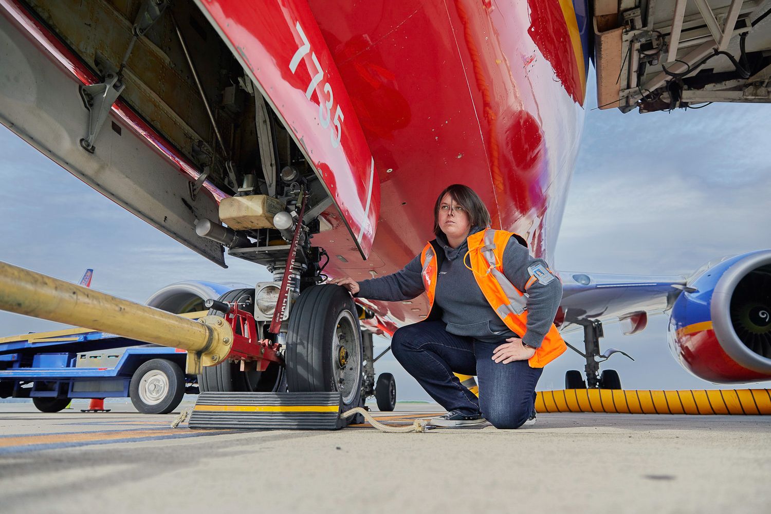 Low angle view of red commercial airplane undercarriage and landing gear during maintenance.
