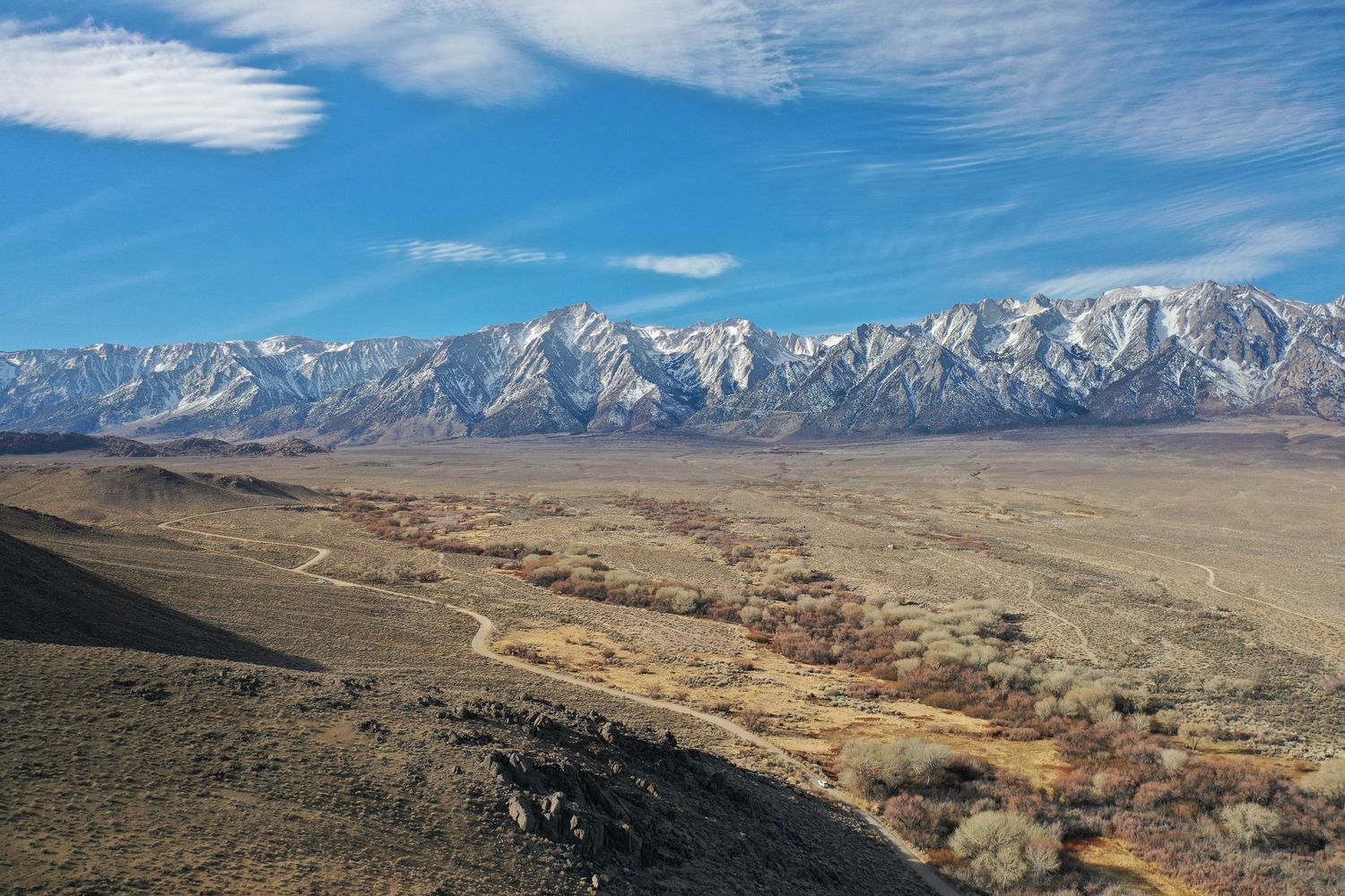 Wide desert valley vista with snow-dusted mountain range stretching across the horizon.