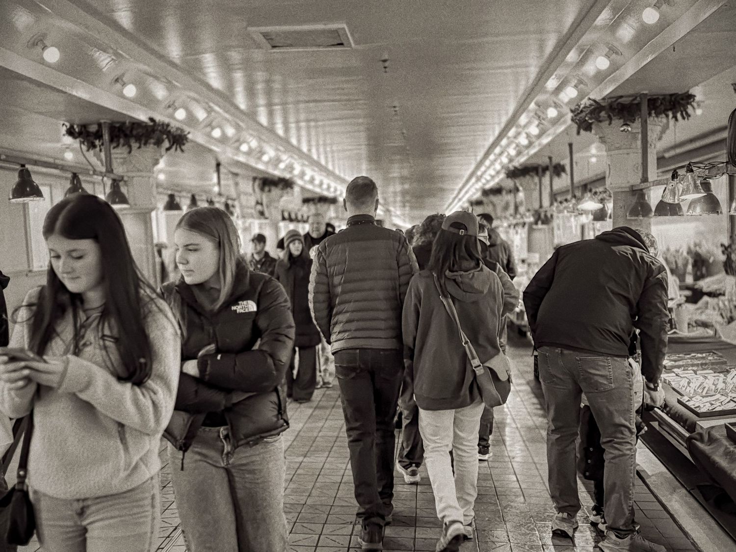 Black and white photograph of commuters walking through a busy underground subway corridor.
