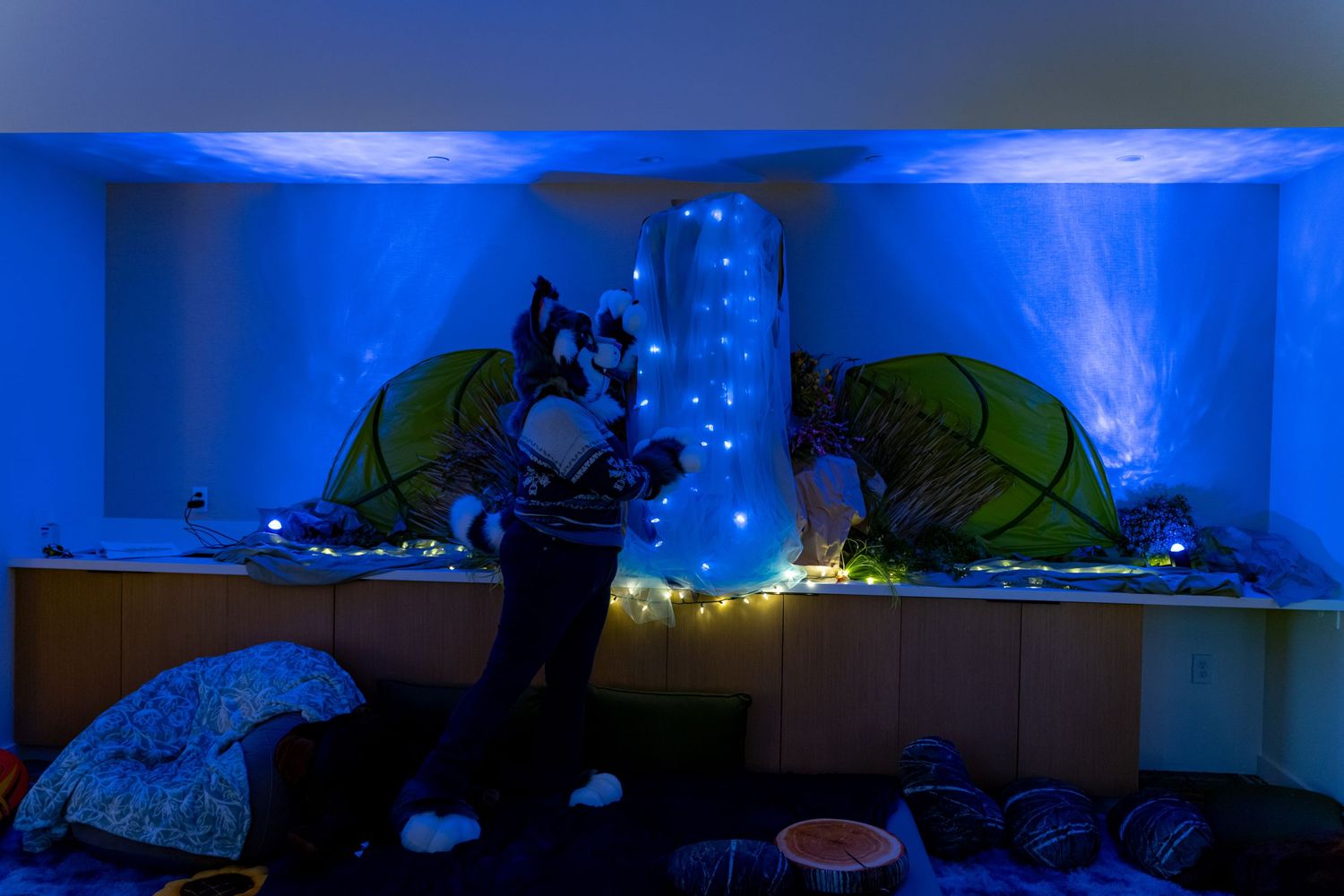 Dark room with blue ambient lighting and illuminated gaming setups creating a moody atmosphere.