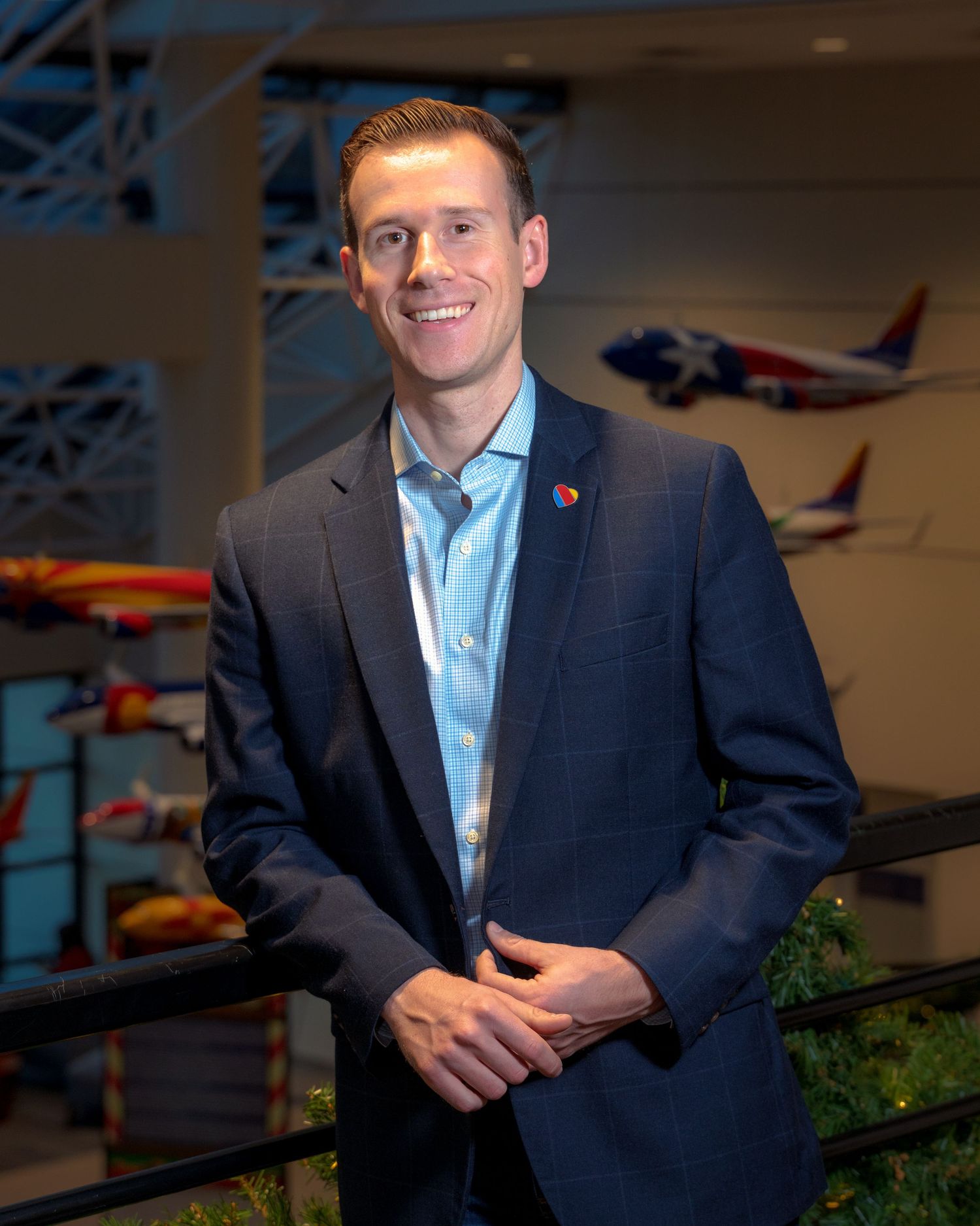 Business professional in navy suit standing in front of display of model airplanes.