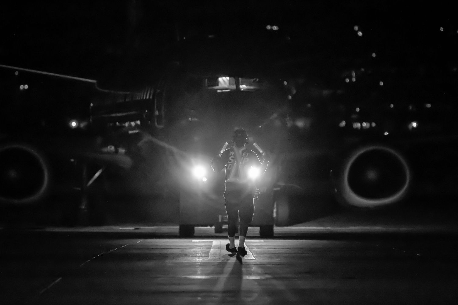 Night scene shows illuminated aircraft on dark runway with lights glowing in the distance.
