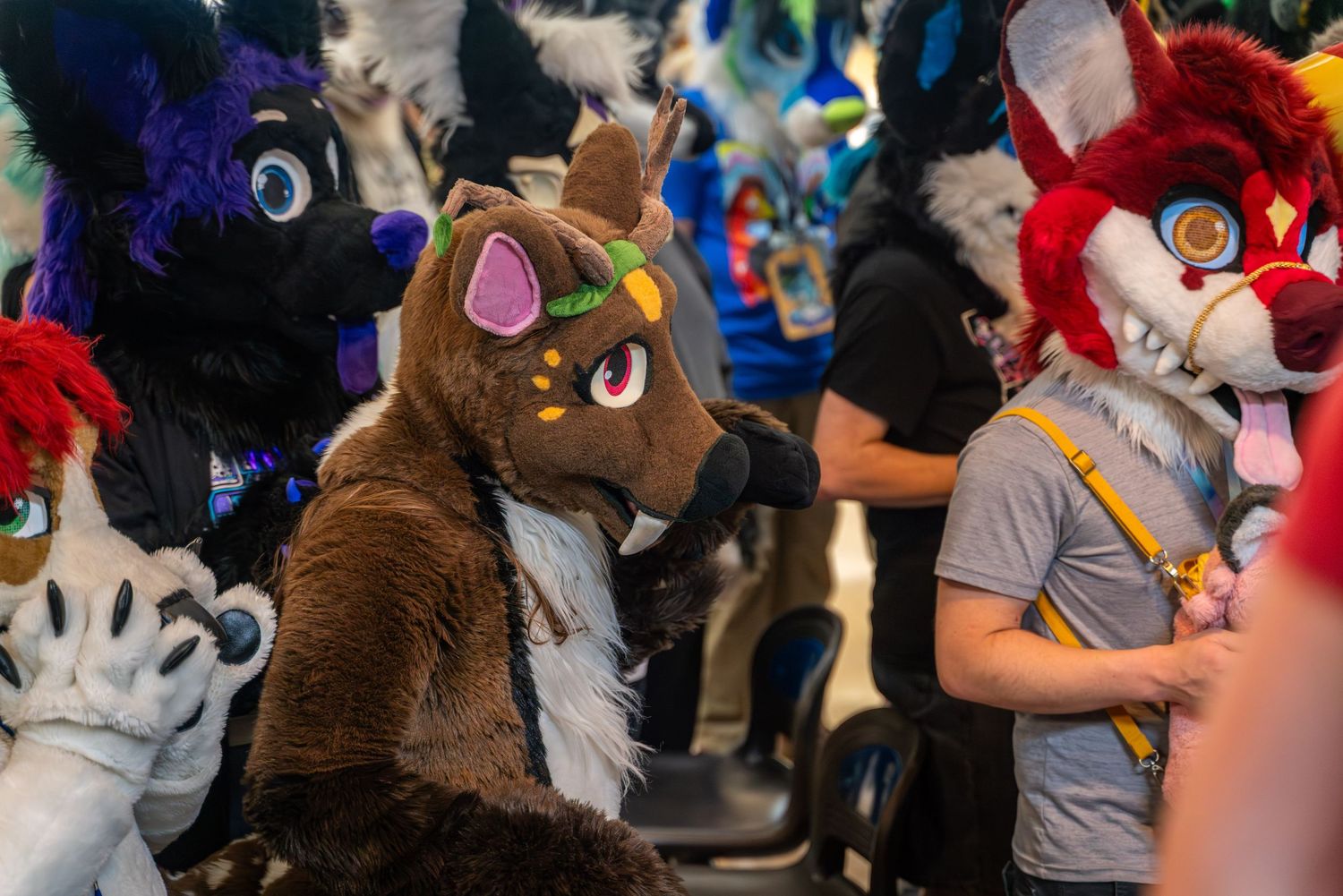 Group of colorful fursuit characters interacting at bowling alley event.